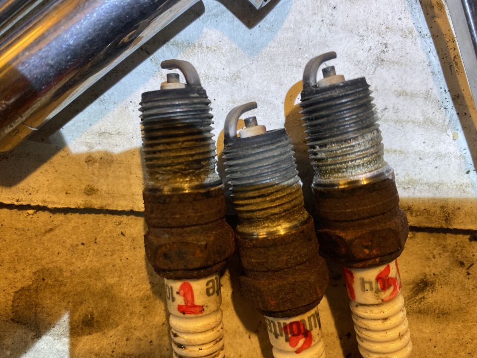 Three rusty spark plugs with red and white markings.
