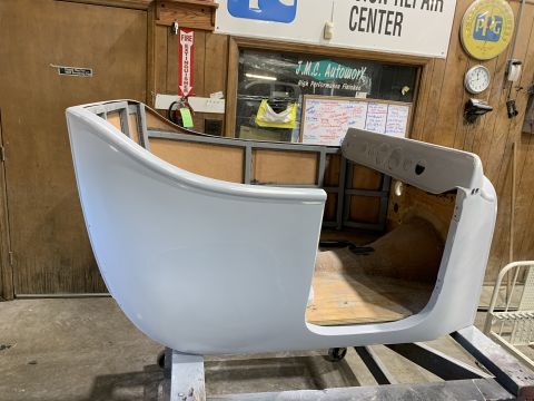 1923 Ford Model T - A light gray, unfinished car body, possibly a roadster or coupe, is shown in a workshop setting. The interior reveals wooden floorboards an…