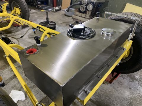 1923 Ford Model T - A custom aluminum fuel tank is mounted on the yellow frame of a hot rod, likely a 1923 Ford Model T, with a tire visible on the right side.…
