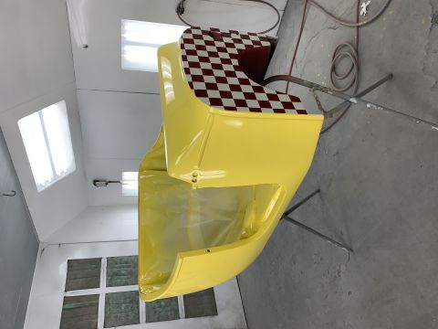 1923 Ford Model T - Glossy yellow fiberglass body panel with a red-and-white checkered insert, hanging in a spray booth.