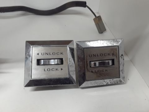 1994 Ford Bronco - Two chrome-trimmed door lock switches with "UNLOCK" and "LOCK" text are shown. A black coiled wire with a gray connector extends from the u…