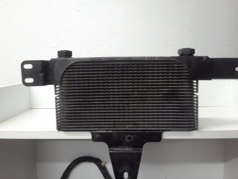 1994 Ford Bronco - A black oil cooler with mounting brackets is shown mounted on a white shelf against a white background. The cooler has a dense array of hor…