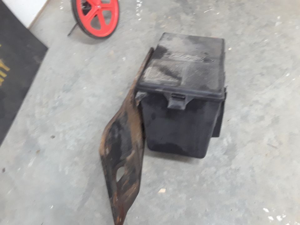 Black Ford fuse box on rusty bracket