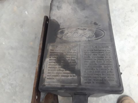 1994 Ford Bronco - A black plastic Ford-branded toolbox is mounted to a metal bracket. The toolbox has warning labels in English and French.