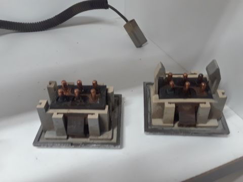 1994 Ford Bronco - Two electrical relay switches with copper terminals are shown on a white surface. A black corrugated wire harness extends from the top left…