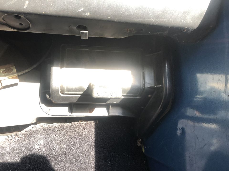 Close-up of a black plastic vent cover labeled "VENT" inside a vehicle.