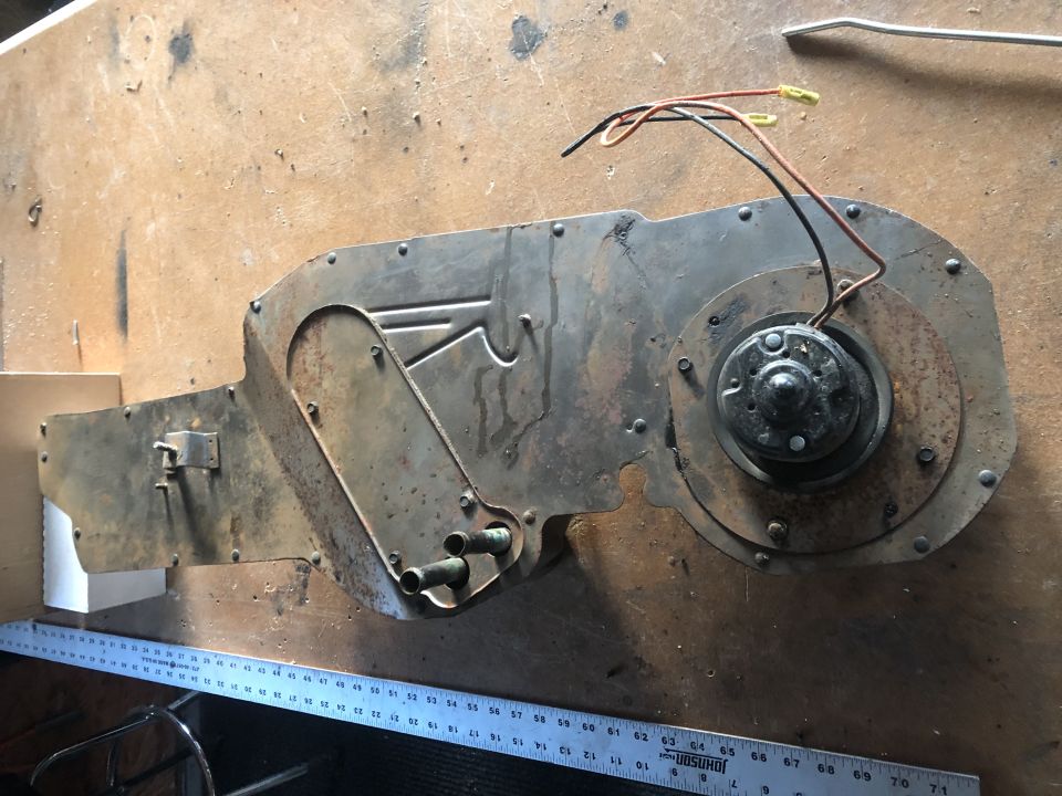 Rusty blower motor assembly with wires and a metal ruler.