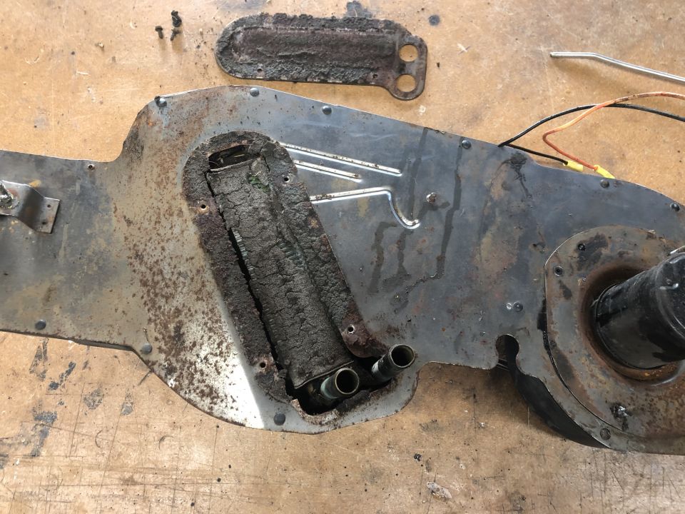 Rusty HVAC blower motor housing and heater core assembly on a wooden surface.