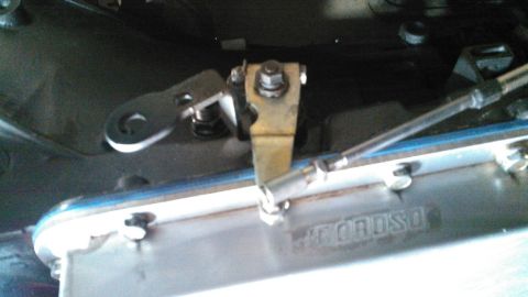 1978 Ford Bronco - A close-up view shows a metal linkage mechanism attached to a vehicle's transmission pan, which has the embossed text "MOROSO" visible. The…
