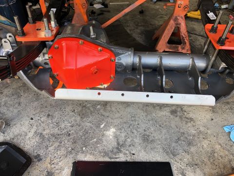 1992 Jeep Wrangler - A close-up view of a vehicle's rear axle assembly, featuring a bright orange differential cover and leaf springs, supported by orange jack…