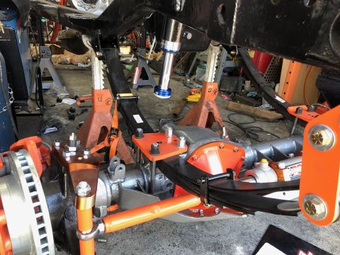 1992 Jeep Wrangler - A close-up view of the undercarriage of a vehicle build, focusing on the suspension system with orange and black components, leaf springs,…