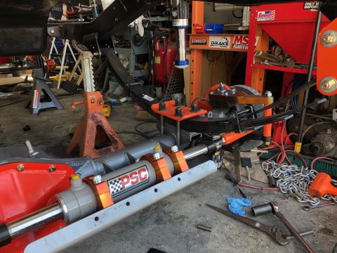 1992 Jeep Wrangler - A hydraulic steering assist cylinder, likely for an off-road vehicle, is shown in a workshop setting with various tools and vehicle parts s…