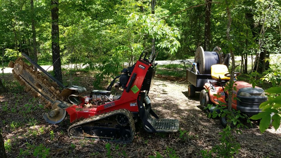 Since I had dug it just a year before with the track-hoe, I was able to use this lighter, cheaper trencher to go back with the bigger cable.  And on the flatter ground near the house, the lawn tractor was easier to pull the trailer with.

After I got it buried, I called again to get connected.  A couple weeks later, they sent out an installer in a van who obviously couldn't do anything.  After a couple of months arguing with them, they finally sent out someone who understood what needed to be done, and then told me it was the wrong cable. But they did offer to install the right cable for $11,000.

After a few more weeks arguing, they decided to try using this cable.  About a month later, it still wasn't connected.