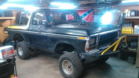 1978 Ford Bronco - This 1978 Ford Bronco is parked indoors, possibly in a garage or workshop, with shelves of supplies in the background.