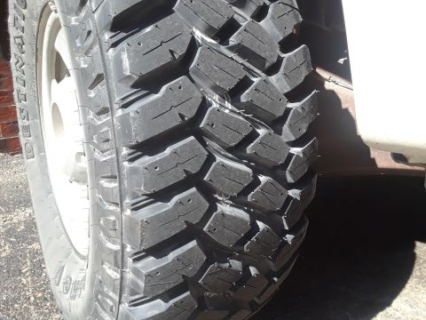 2008 Ford F-350 - A close-up view of a heavy-duty off-road tire mounted on a white vehicle's wheel.