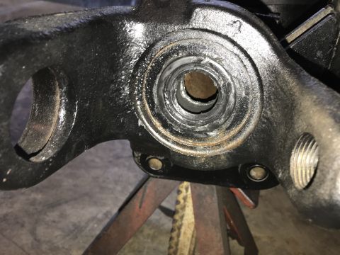 1989 Ford Bronco - Close-up of a worn automotive suspension part, likely a knuckle or spindle, showing internal wear and grease residue.