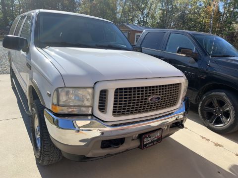 2009 Harley-Davidson FLH - Front view of a white Ford Excursion SUV parked next to a black pickup truck.