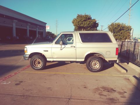1996 Ford Bronco - Side view of a silver SUV, likely a Ford Bronco from the early 1990s, parked in a lot.