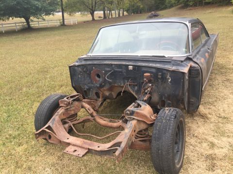 1961 Ford Starliner - This 1961 Ford Starliner is missing its engine and front clip, resting on its frame in a field.