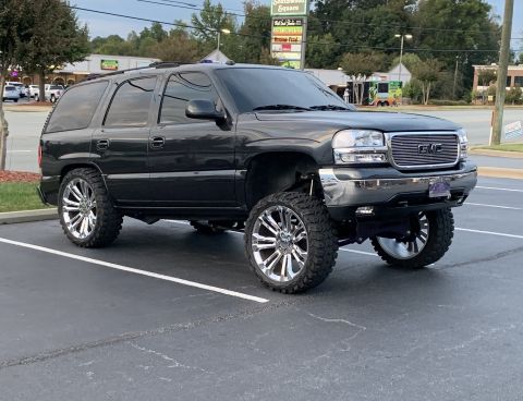 2009 Harley-Davidson FLH - A lifted black GMC Yukon XL with chrome wheels is parked in a lot under a cloudy sky.