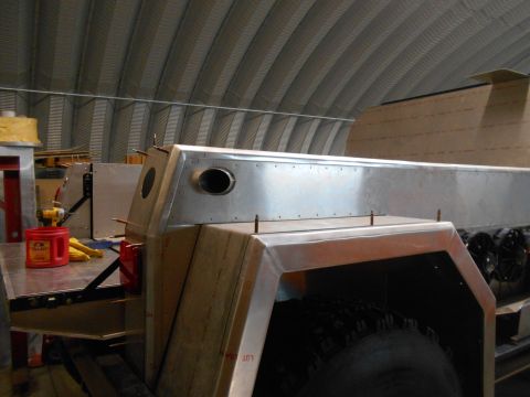 1992 Ford Bronco - The custom metal body of a vehicle is being constructed, with visible rivets and a vent on its side.