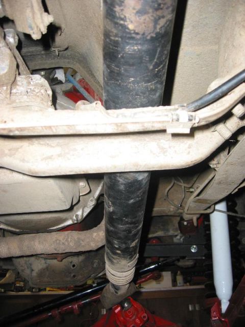 1985 Ford Bronco - Close-up of the undercarriage, focusing on the driveshaft and suspension parts of a vehicle.