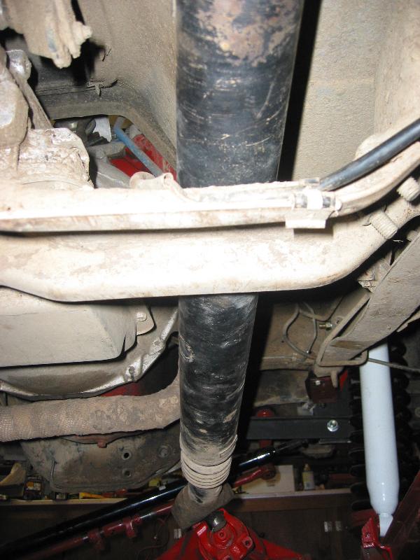 Undercarriage view showing driveshaft, dusty crossmember, and white shock absorber