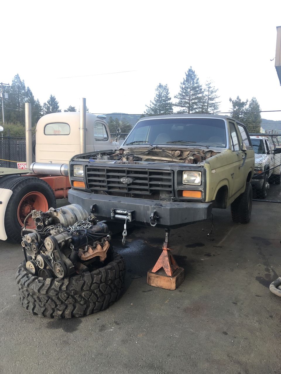 Tan SUV with hood open, engine removed, and aftermarket bumper. Seen from front