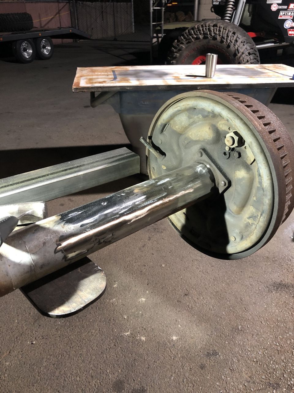 Rear axle assembly with brake drum, showing metal fabrication and rust