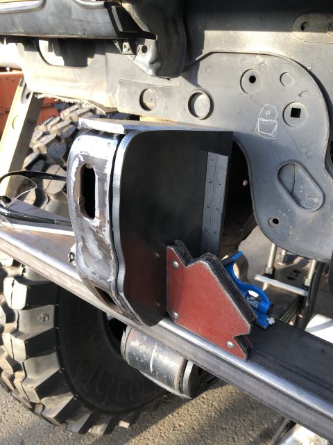 1986 Ford Bronco - A close-up shot shows a metal bracket being prepared for welding onto a vehicle's frame, with a ruler for precise measurement.