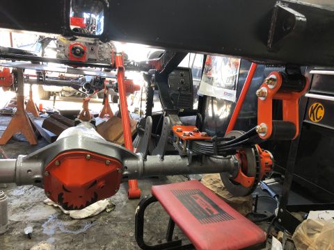 1992 Jeep Wrangler - Rear axle assembly with orange differential cover and leaf springs, undergoing work.