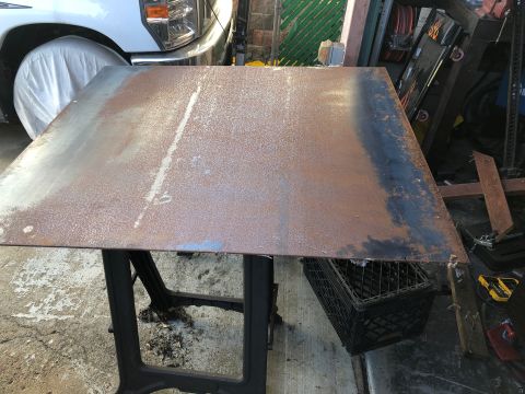 1992 Jeep Wrangler - A large, rusted metal sheet rests on a black stand in a garage setting, with a portion of a white truck visible in the background.