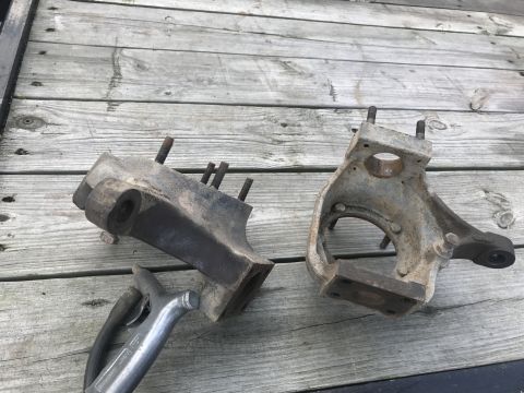 1989 Ford Bronco - Two vehicle suspension parts, possibly from a Ford Bronco, are laid out on a wooden deck.