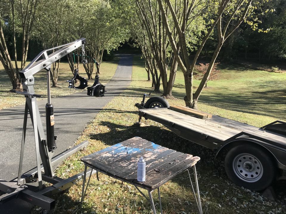engine hoist next to a trailer and a table with a spray can