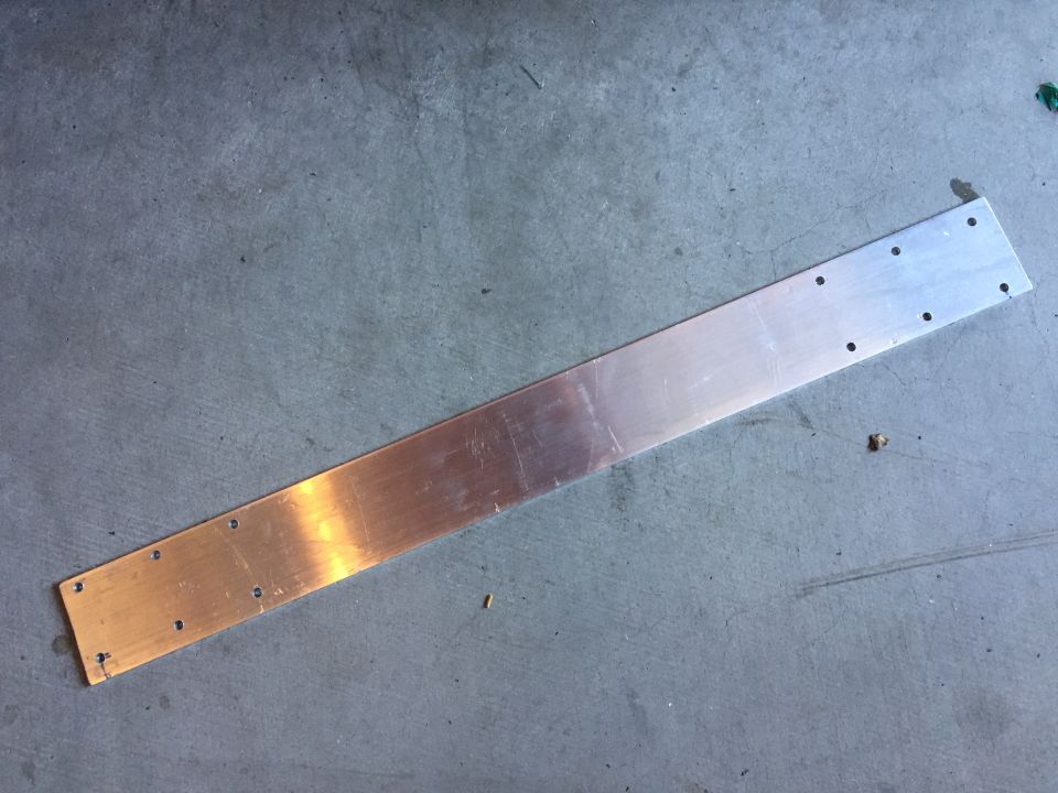 metal bracket with holes, on concrete floor. Supermotors.net logo in corner