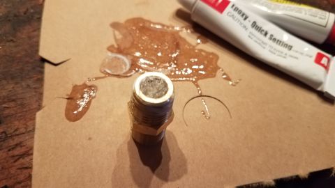 1985 Ford Bronco - Epoxy and a threaded fitting are shown on a piece of paper, with tubes of epoxy in the background.