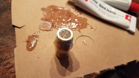 1985 Ford Bronco - A DIY leakdown tester is being assembled with epoxy on a piece of cardboard.