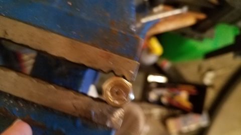 1985 Ford Bronco - A small, round metal component is secured in a vise, ready for work.