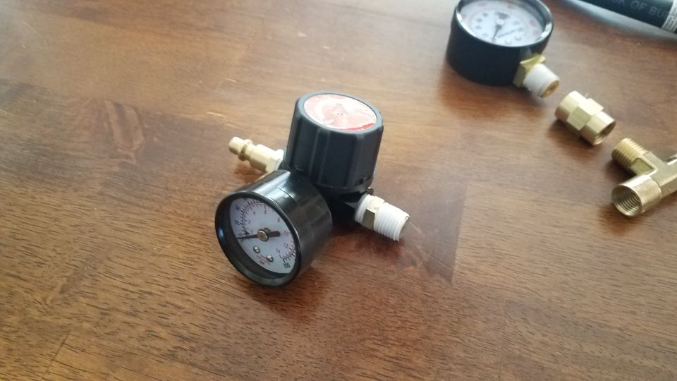 Air pressure regulator with two gauges and brass fittings on a wooden surface