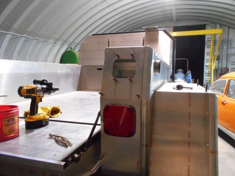 1992 Ford Bronco - An unfinished aluminum truck bed is in a workshop, with a drill and a red container on its surface.