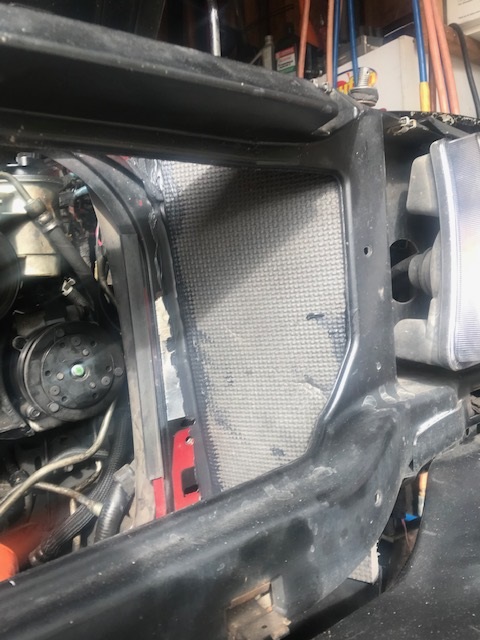 2000 Ford Explorer - The engine bay reveals the radiator and AC compressor, surrounded by black metal structural components.