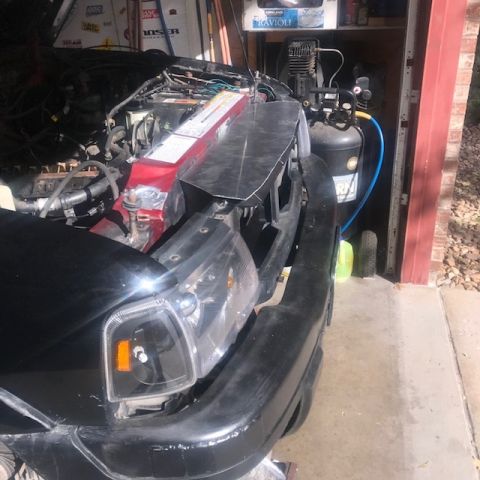 2000 Ford Explorer - The front of a vehicle is disassembled in a garage, with an air compressor nearby.