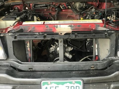2000 Ford Explorer - The engine bay of a red vehicle is visible with the radiator removed, revealing engine parts.