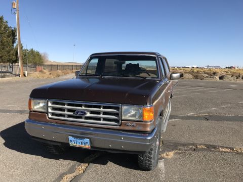 1988 Ford Bronco - Front 3/4 view of a brown Ford Bronco with a chrome bumper and grille.