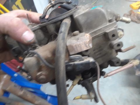 1994 Ford Bronco - A close-up view of a carburetor, likely removed from a vehicle for repair or replacement.