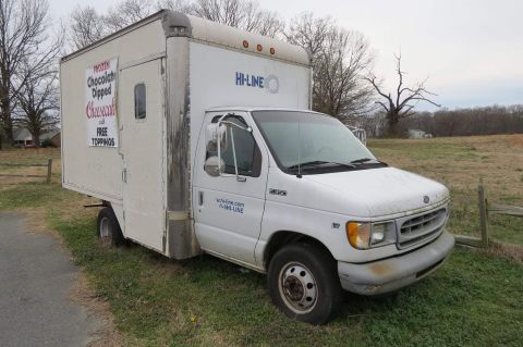 1998 Ford E350 - A white 1998 Ford E350 box truck is parked on a grassy area with a cheesecake advertisement on its side.