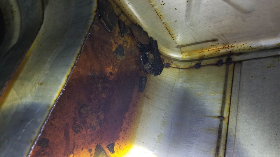 Rusted metal interior with dark stains and debris