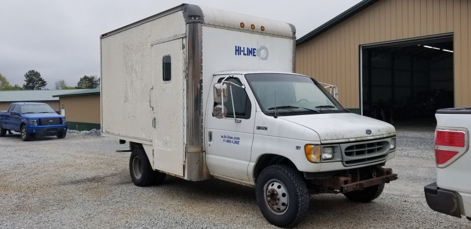 1998 Ford E350 box truck with 'HI-LINE' logo on the side, parked next to a blue Ford F-150 pickup
