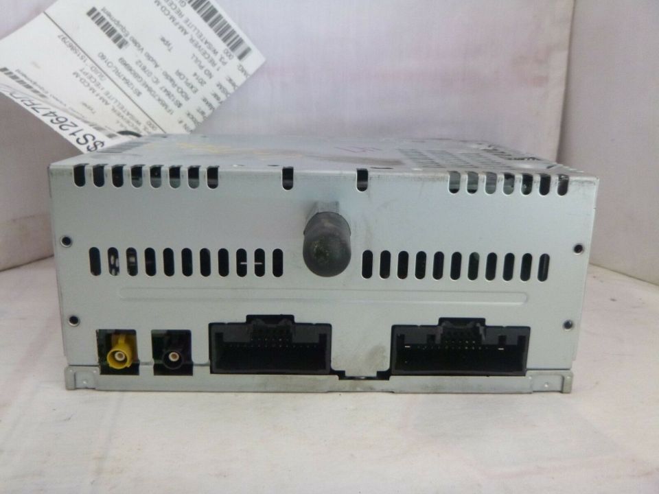 Back of a silver Ford radio receiver module with two black harness connectors, antenna ports, and a salvage tag