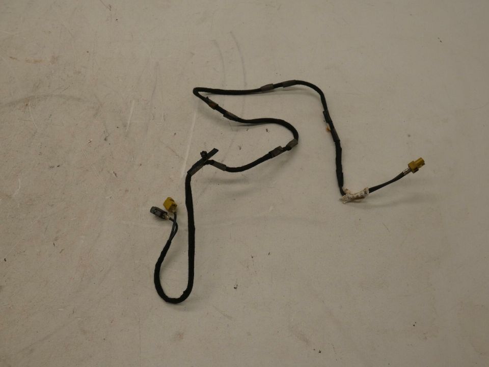 Black wiring harness with yellow connectors and paper label laid on gray floor